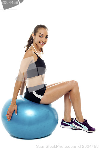 Image of Pretty woman relaxing on big blue exercise ball