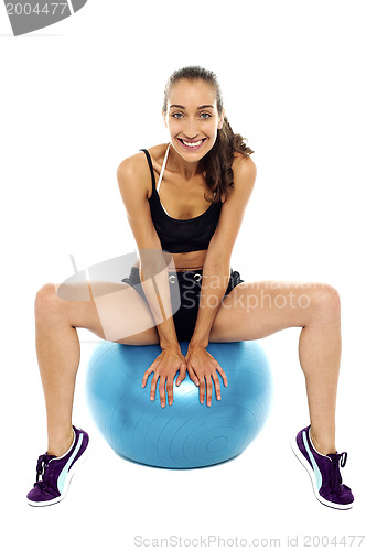Image of Beautiful smiling fit lady relaxing on big swiss ball