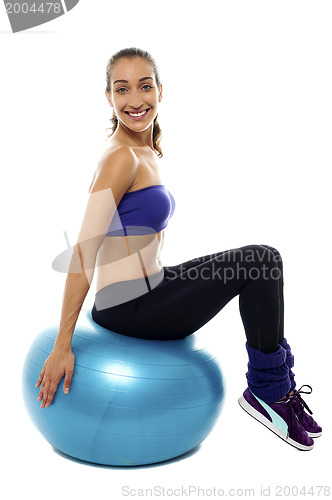 Image of Pretty lady sitting on big blue exercise ball
