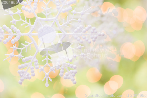 Image of Snowflake Over an Abstract Green and Gold Background