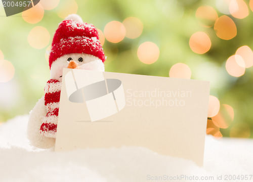 Image of Cute Snowman with Blank White Card Over Abstract Background
