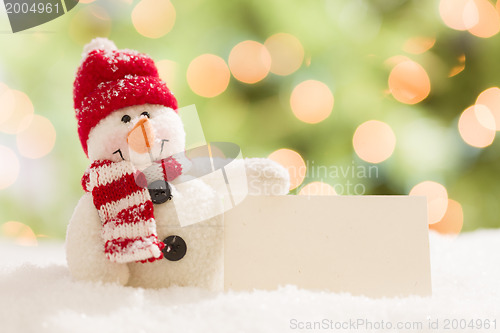 Image of Cute Snowman with Blank White Card Over Abstract Background