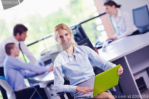 Image of business woman with her staff in background at office