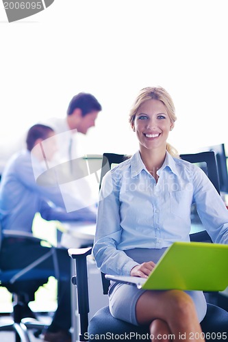 Image of business woman with her staff in background at office