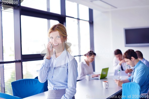 Image of business woman with her staff in background at office
