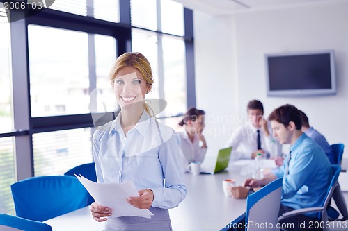Image of business woman with her staff in background at office