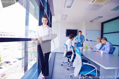 Image of business woman with her staff in background at office