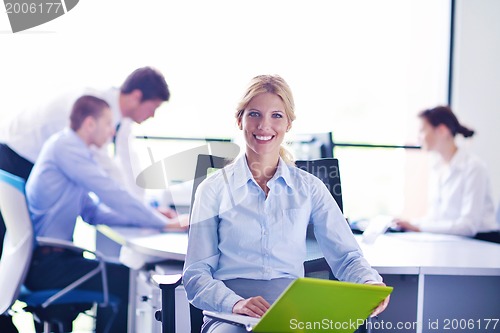 Image of business woman with her staff in background at office