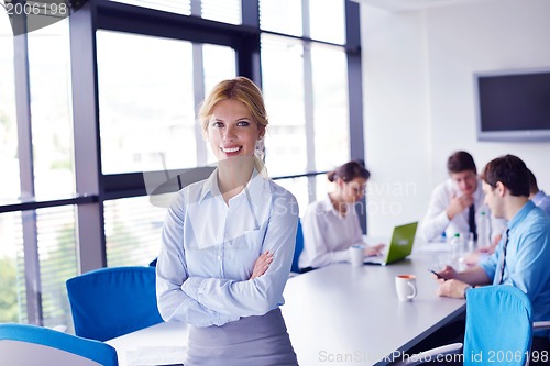 Image of business woman with her staff in background at office
