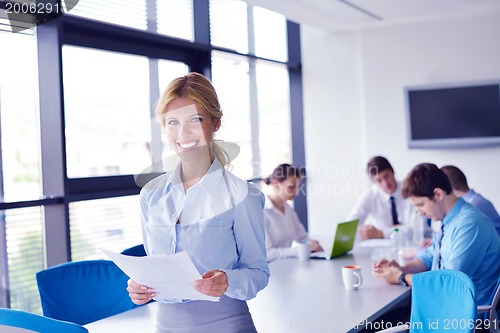 Image of business woman with her staff in background at office