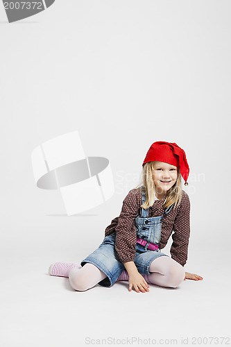 Image of Smiling girl wearing Christmas hat sitting