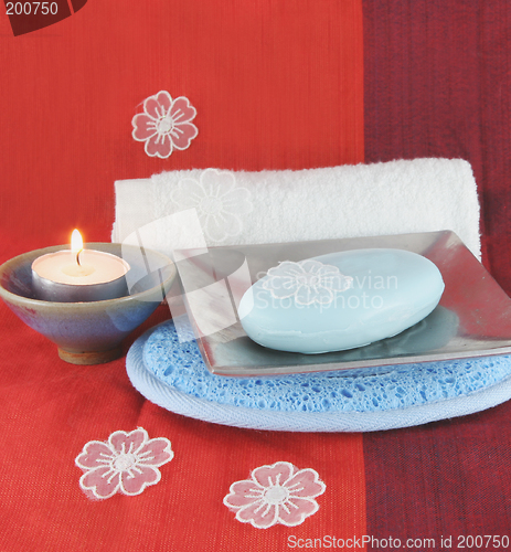 Image of Burning candle and white flowers with soap in a dish