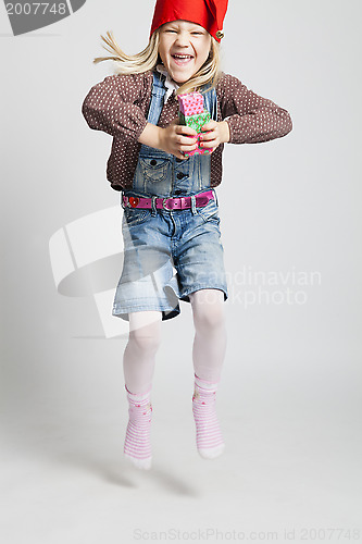 Image of Happy girl jumping while holding Christmas gifts