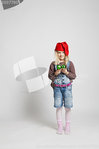 Image of Smiling girl wearing Christmas hat and holding baubles