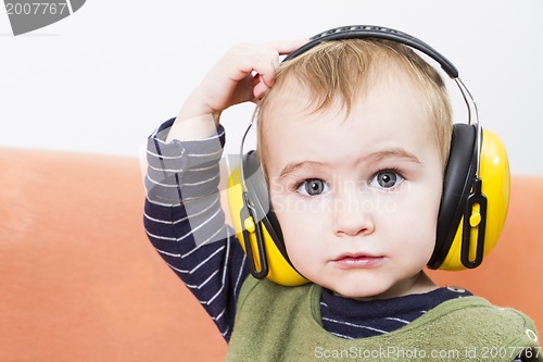 Image of young child on couch with earmuffs