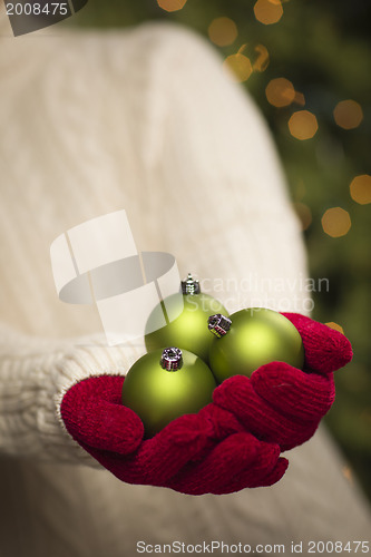 Image of Woman Wearing Seasonal Red Mittens Holding Green Christmas Ornam