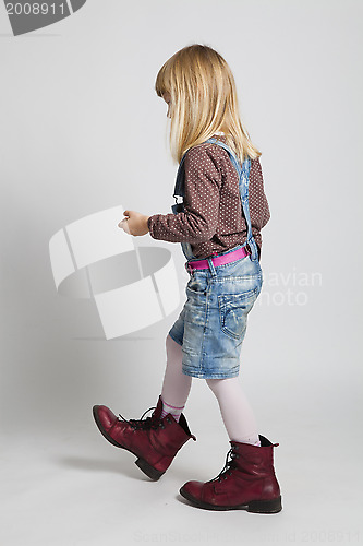 Image of Young girl walking in adult sized boots
