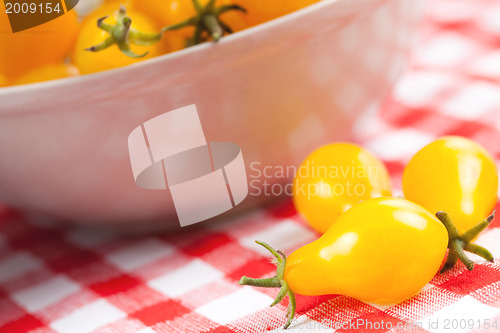 Image of yellow tomatoes on picnic tablecloth