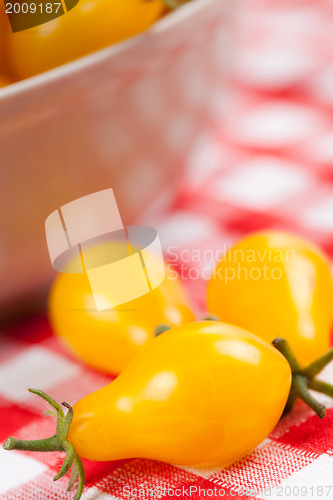 Image of yellow tomatoes on picnic tablecloth