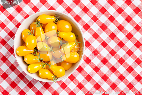 Image of yellow tomatoes on picnic tablecloth