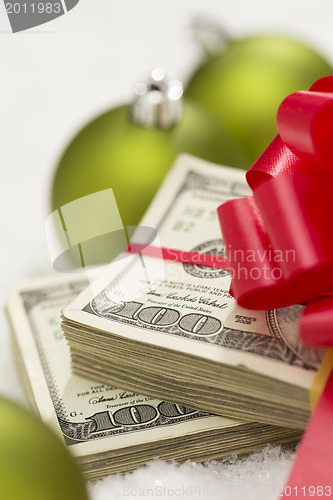 Image of Stack of Hundred Dollar Bills with Bow Near Christmas Ornaments
