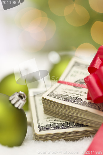 Image of Stack of Hundred Dollar Bills with Bow Near Christmas Ornaments