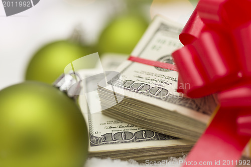 Image of Stack of Hundred Dollar Bills with Bow Near Christmas Ornaments