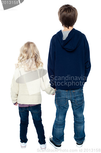 Image of Rear view of two little kids. Boy holding his sister.