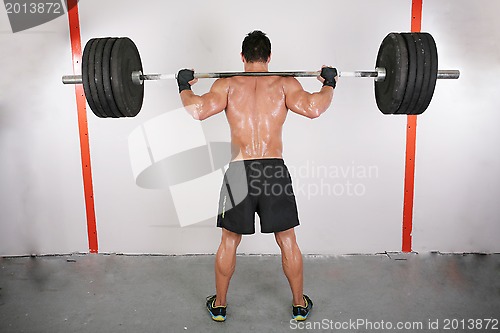 Image of arms and back of a young muscular man working out with a bar