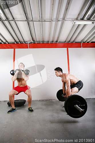 Image of Group of two people exercising using barbells in gym and kettleb