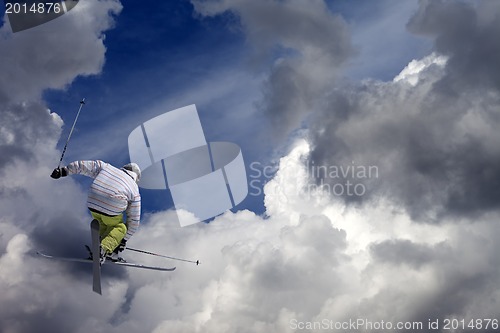 Image of Freestyle ski jumper with crossed skis against blue sky with clo