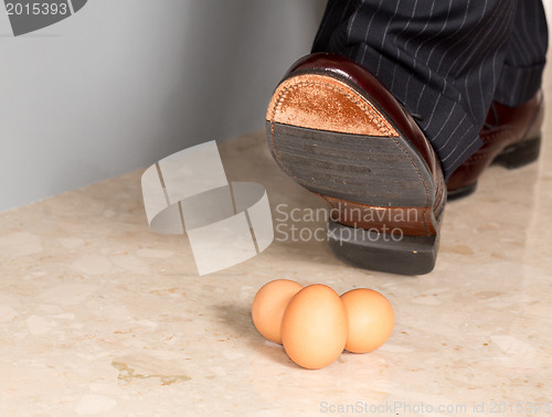 Image of Man's shoe stamping on three eggs