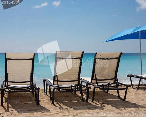 Image of Three beach loungers and umbrella on sand