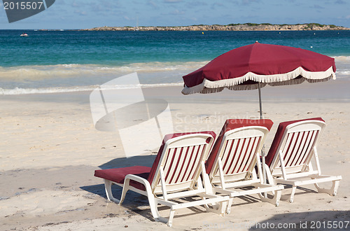 Image of Three beach loungers and umbrella on sand