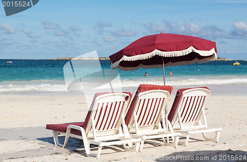 Image of Three beach loungers and umbrella on sand