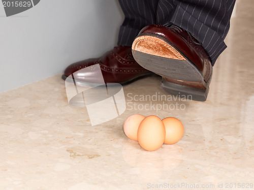Image of Man's shoe stamping on three eggs