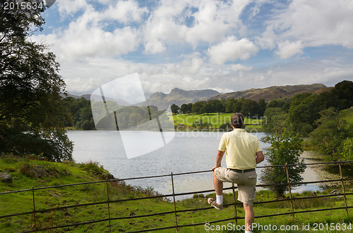 Image of Hiker overlooks Loughrigg Tarn in Lake District