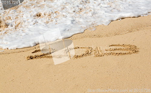 Image of 2013 written in sand with waves