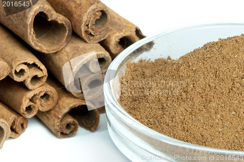 Image of Powdered cinnamon in bowl and cinnamon sticks