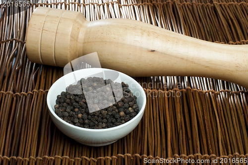 Image of Bowl with black pepper and wooden pepper mill