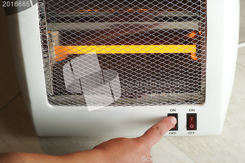 Image of Electric heater and hand which includes switch