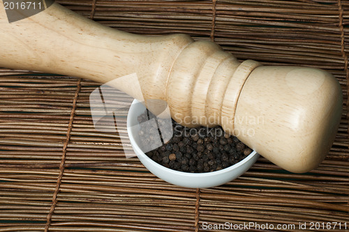 Image of Bowl with black pepper and wooden pepper mill