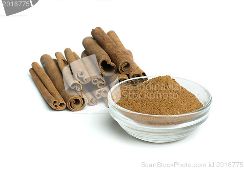 Image of Powdered cinnamon in bowl and cinnamon sticks