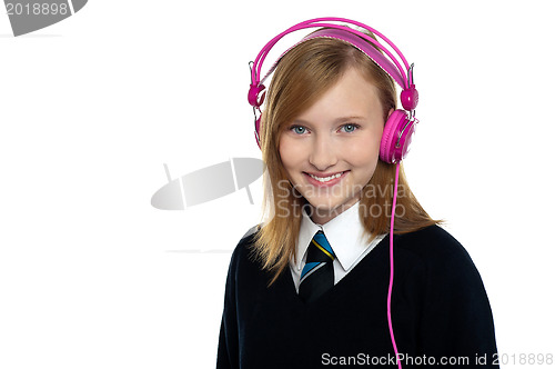 Image of Cute teenager listening to music through headphones