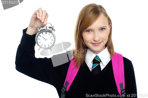 Image of Pretty charming schoolgirl holding time piece