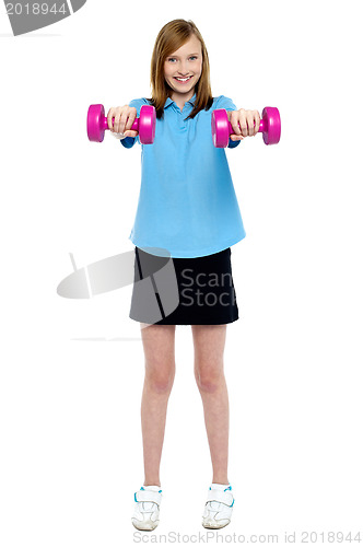 Image of Slim girl striking a pose with dumbbells. Lifting weights