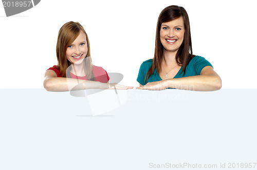 Image of Lady with daughter posing behind blank billboard