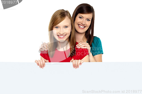 Image of Girl holding ad board with her mother behind her