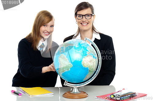 Image of Teacher and student viewing globe in geography classroom