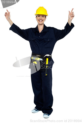 Image of Smiling lady worker in jumpsuit raising her hands